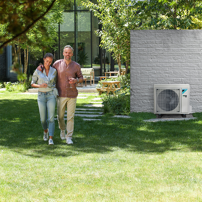 Daikin Comfora buitenunit in de tuin. Energie-efficiënt, stil en milieuvriendelijk. Perfect voor wie zoekt naar stille, duurzame airco voor huis of kantoor.