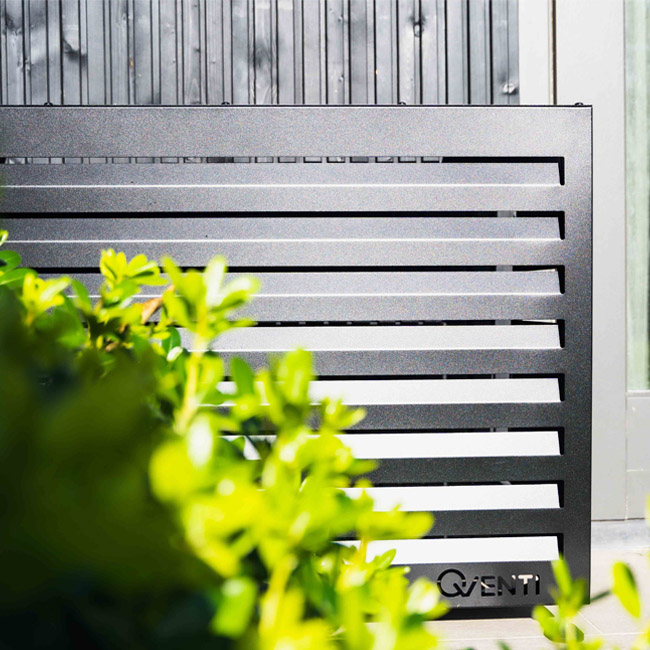 airco omkasting zwart achter een struik